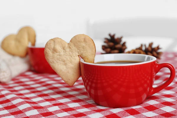 Galleta en forma de corazón en taza de café en primer plano servilleta a cuadros —  Fotos de Stock