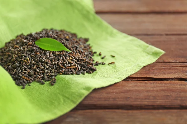 Chá granulado com folhas verdes em pano de saco close-up — Fotografia de Stock
