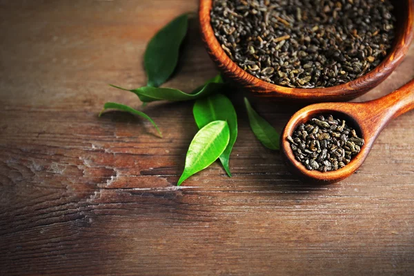 Granulated tea with green leaves in wooden bowl on table closeup — Stock Photo, Image