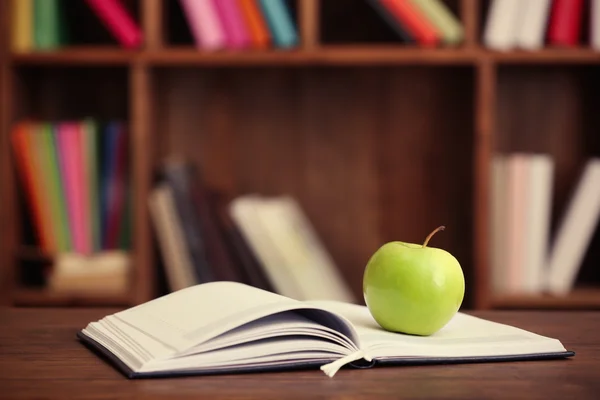 Apfel und aufgeschlagenes Buch auf dem Tisch, Nahaufnahme — Stockfoto