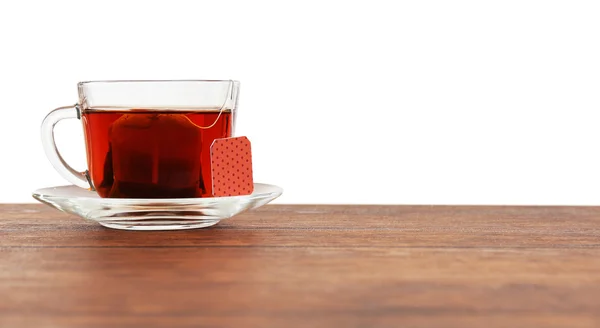 Стеклянная чашка с пакетиком чая на деревянном столе на белом фоне — стоковое фото