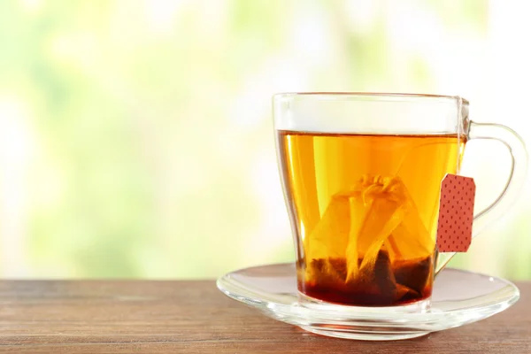 Glass cup with tea bag on wooden table, close up — Stock Photo, Image