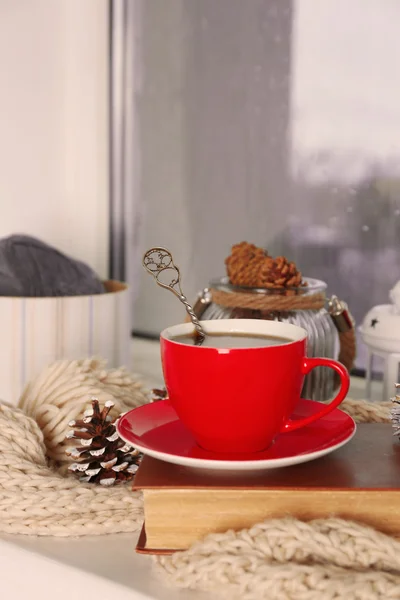 Una taza de bebida caliente en el alféizar de la ventana en la sala de estar. Cómodo fin de semana de invierno o vacaciones en casa — Foto de Stock