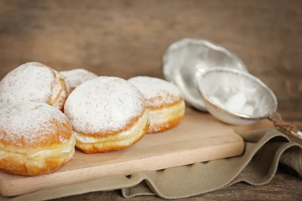 Delicious sugary donuts on wooden cutting board closeup — Stock Photo, Image