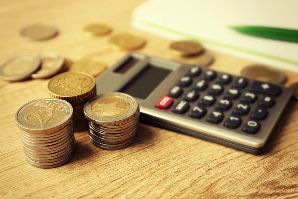 Conceito de dinheiro. Calculadora cinza com moedas e notebook em mesa de madeira — Fotografia de Stock