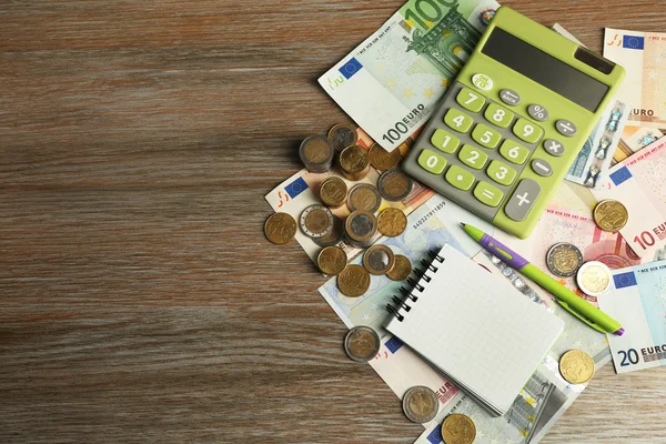 Geld concept. Groene calculator met bankbiljetten en munten op houten tafel — Stockfoto