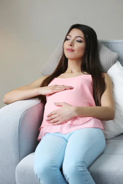 Kobieta w ciąży odpoczynku na kanapie w pokoju — Zdjęcie stockowe