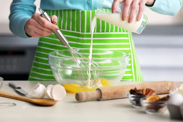 Young woman adding a milk to the egg mixture — Stock Photo, Image