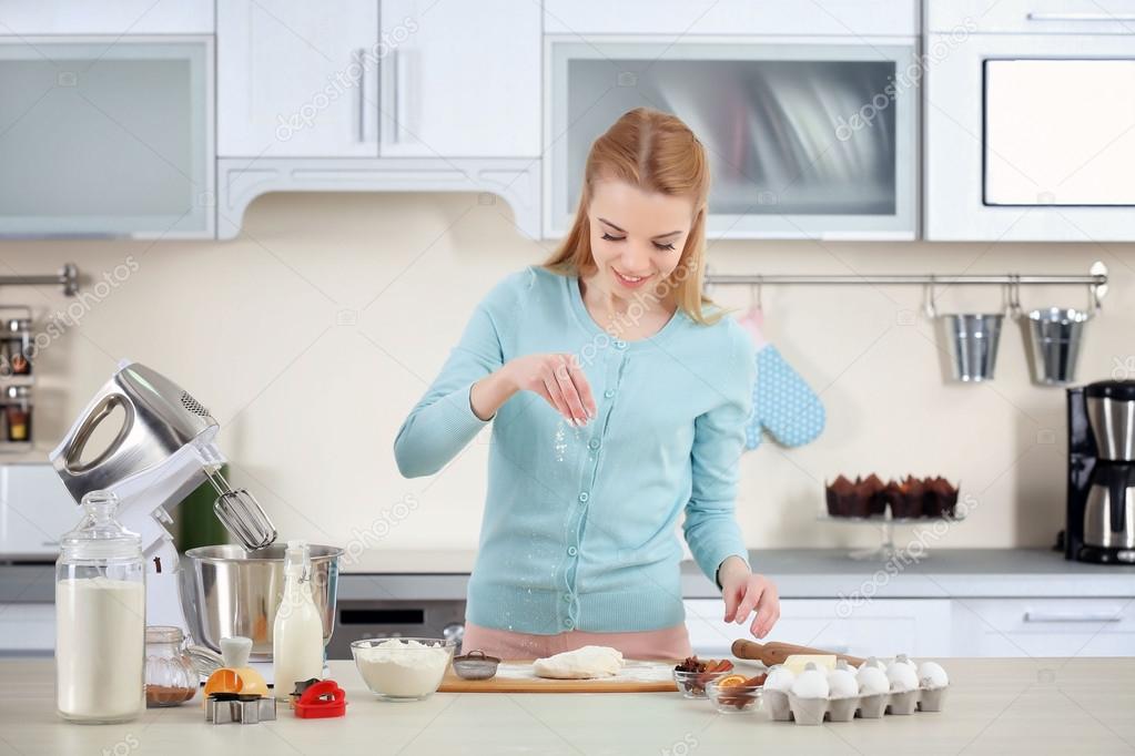 Young woman rolling out the dough on the kitchen counter