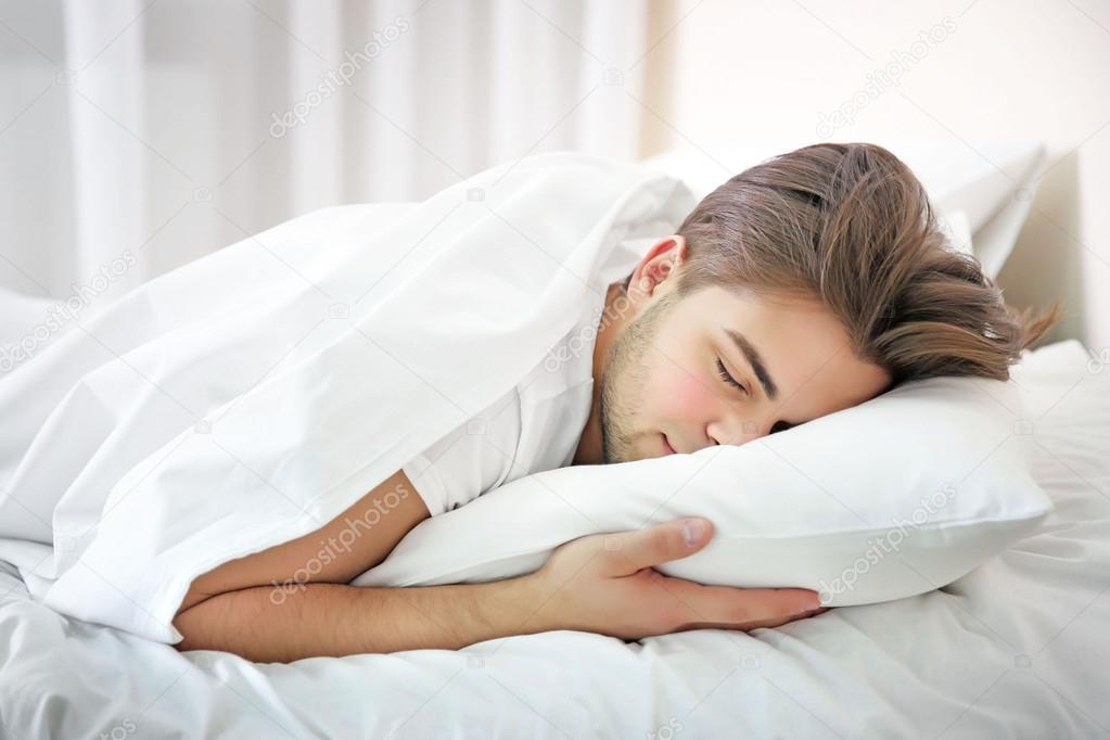 Young man sleeping in bed at home