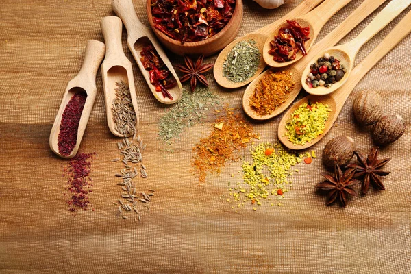 Assorted spices in spoons on wooden table, top view — Stock Photo, Image