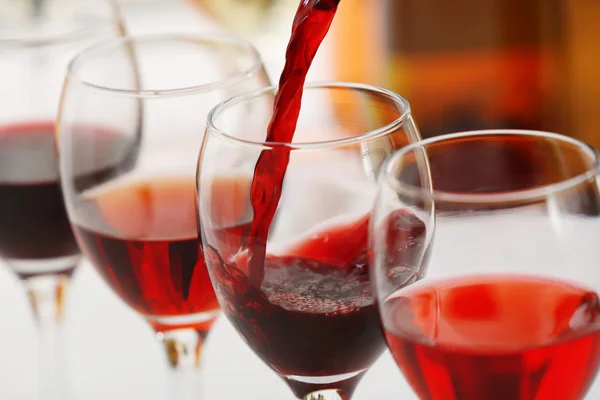 Red wine pouring into glasses, closeup — Stock Photo, Image