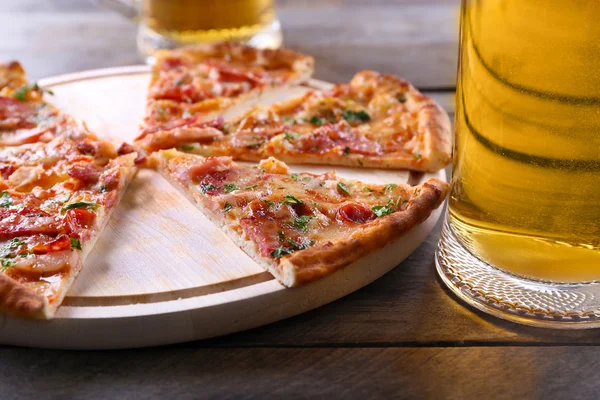 Pizza en rodajas y vaso de cerveza sobre mesa de madera, de cerca — Foto de Stock