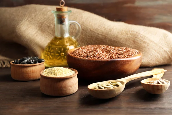 Semillas de lino, sésamo, calabaza y girasol con aceite sobre fondo de mesa de madera, primer plano —  Fotos de Stock