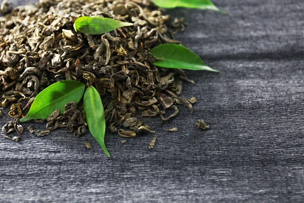 Gekorrelde thee met groene bladeren op een grijze achtergrond — Stockfoto