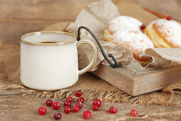 Délicieux beignets sucrés avec groseille rouge sur plateau en bois avec parchemin gros plan — Photo