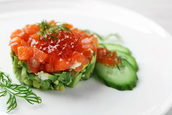 Delicious salmon tartare with red caviar on white plate — Stock Photo, Image