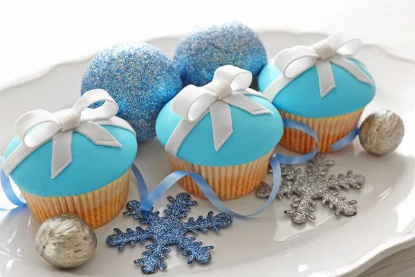 Sabrosos cupcakes con arco y juguetes de Navidad sobre fondo de madera de color —  Fotos de Stock