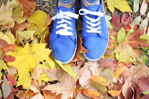 Woman in trainers standing on foliage — Stock Photo, Image