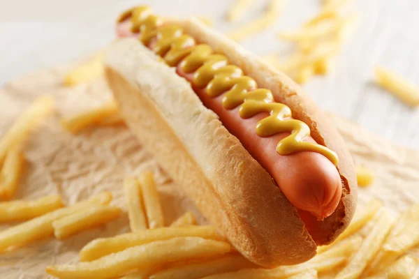 Cachorro quente e batatas fritas no fundo de madeira — Fotografia de Stock