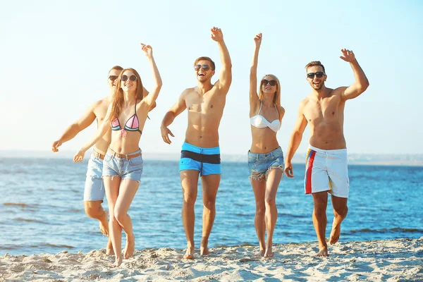 Amigos felices corriendo en la playa — Foto de Stock