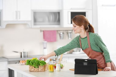 Genç bir kadın mutfakta yemek pişiriyor.