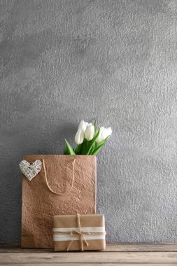 Kağıt torba gri duvara ahşap masa üzerinde beyaz laleler yakın çekim