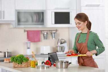 Genç bir kadın mutfakta yemek pişiriyor.