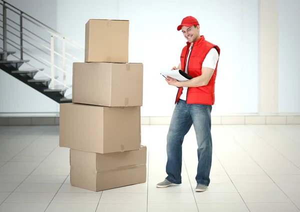 Postbote in roter Jacke in der Nähe von Kisten — Stockfoto