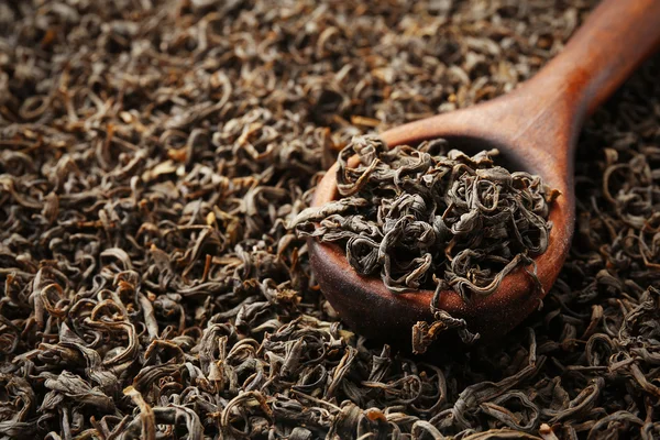 Pilha de chá seco com colher de madeira, close-up — Fotografia de Stock