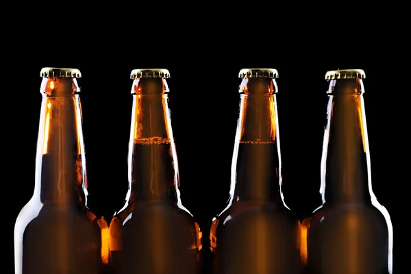 Four bottles of beer on black background — Stock Photo, Image