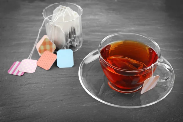 Cup of tea with tea bags on grey background — Stock Photo, Image