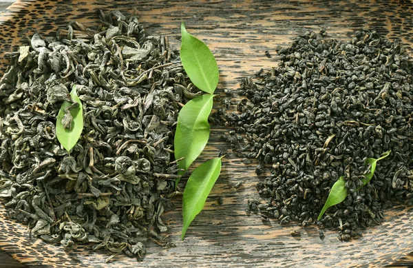 Trockener Tee im Teller mit grünen Blättern, Nahaufnahme — Stockfoto