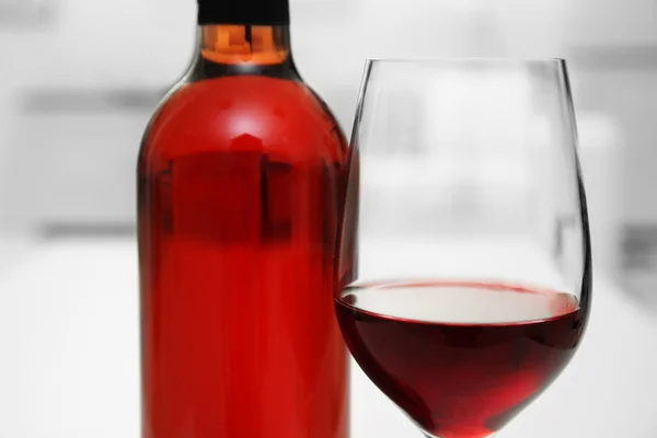 Glas Rotwein mit Flasche auf verschwommenem Innenhintergrund — Stockfoto