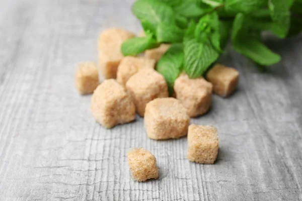 Montón de terrones de azúcar moreno y stevia sobre fondo de madera gris — Foto de Stock