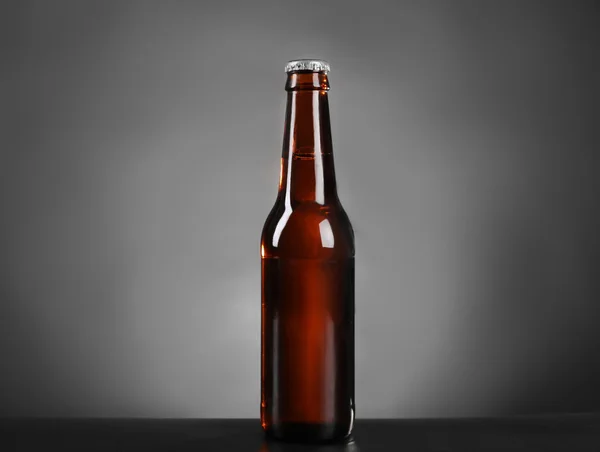 Glass bottle of dark beer on grey background — Stock Photo, Image