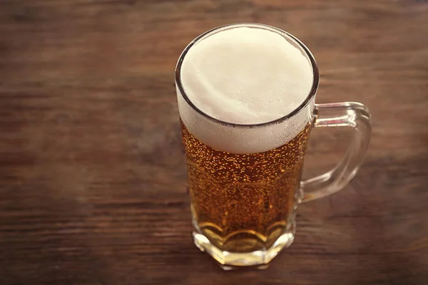 Glas helles Bier auf hölzernem Hintergrund — Stockfoto