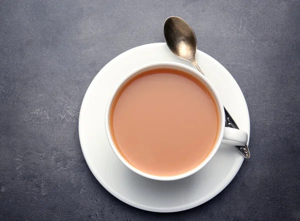 Porcellana tazza di tè con latte su sfondo grigio — Foto Stock