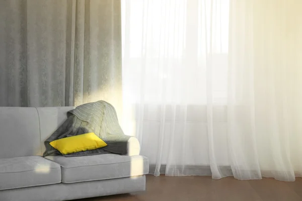 Серый диван с желтой подушкой — стоковое фото