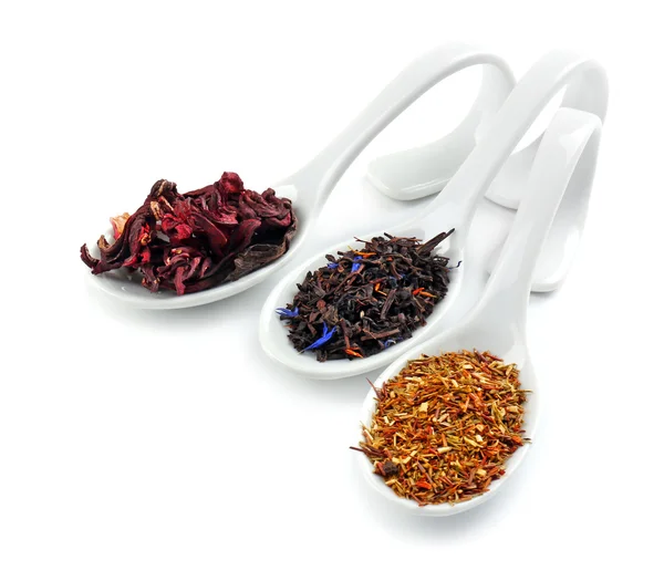 Verschillende soorten droge thee in keramische lepels, geïsoleerd op wit — Stockfoto