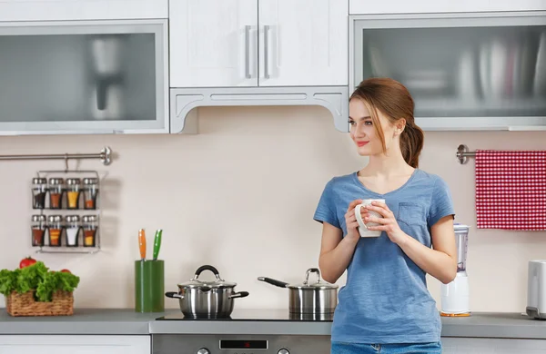 Mujer sosteniendo taza en la cocina —  Fotos de Stock