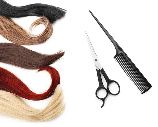 Ножницы с расчёской и разноцветными прядями волос — стоковое фото