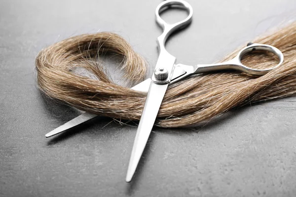 Ножницы с прядью каштановых волос — стоковое фото