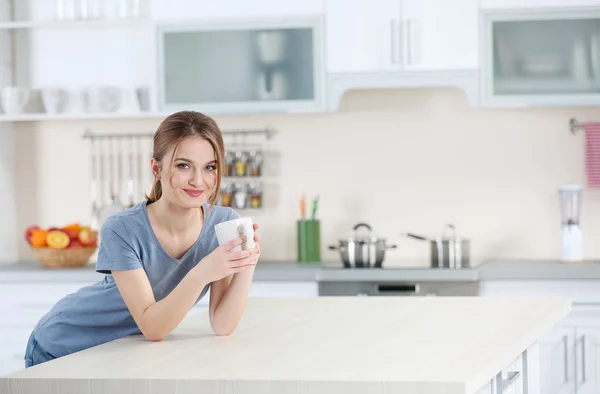 Женщина держит чашку на кухне — стоковое фото