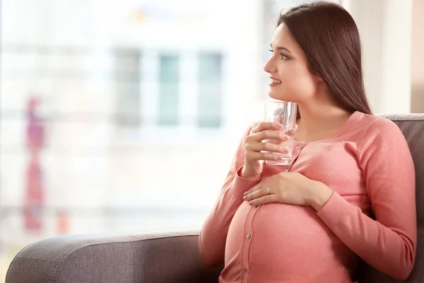 Беременная женщина со стаканом воды — стоковое фото