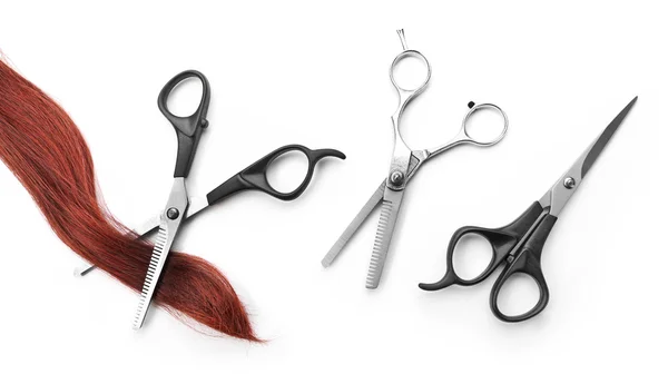 Kadeřnické nůžky s pramen zrzavé vlasy, izolovaných na bílém — Stock fotografie