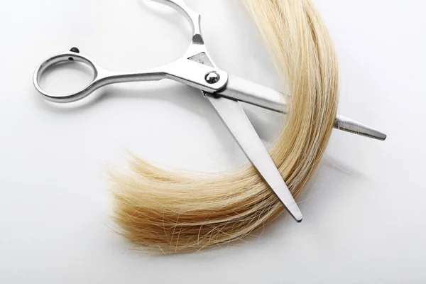 Tesoura de cabeleireiro com fio de cabelo loiro, isolado em branco — Fotografia de Stock