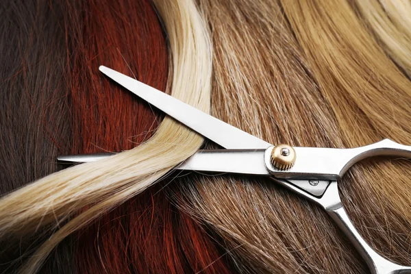 Ножницы парикмахера с разноцветными прядями волос, закрыть — стоковое фото