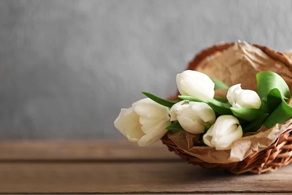 Tulipanes blancos en una canasta de mimbre sobre una mesa de madera, de cerca —  Fotos de Stock