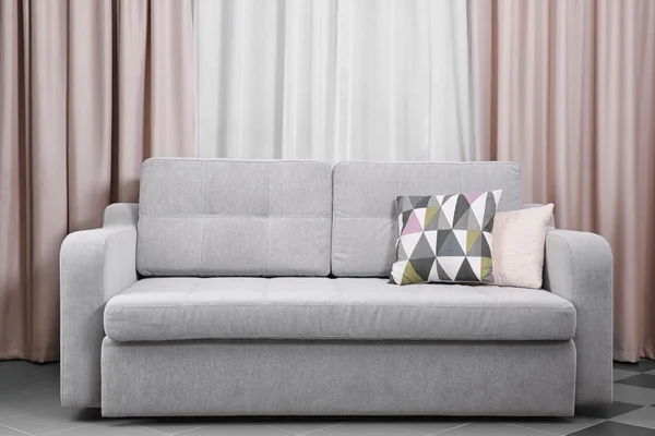 Graues Sofa gegen Vorhänge — Stockfoto